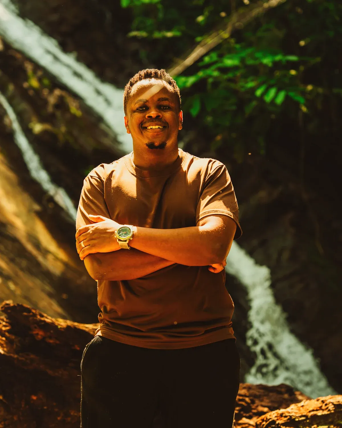 Jordan Mtui standing in front of a forest waterfall