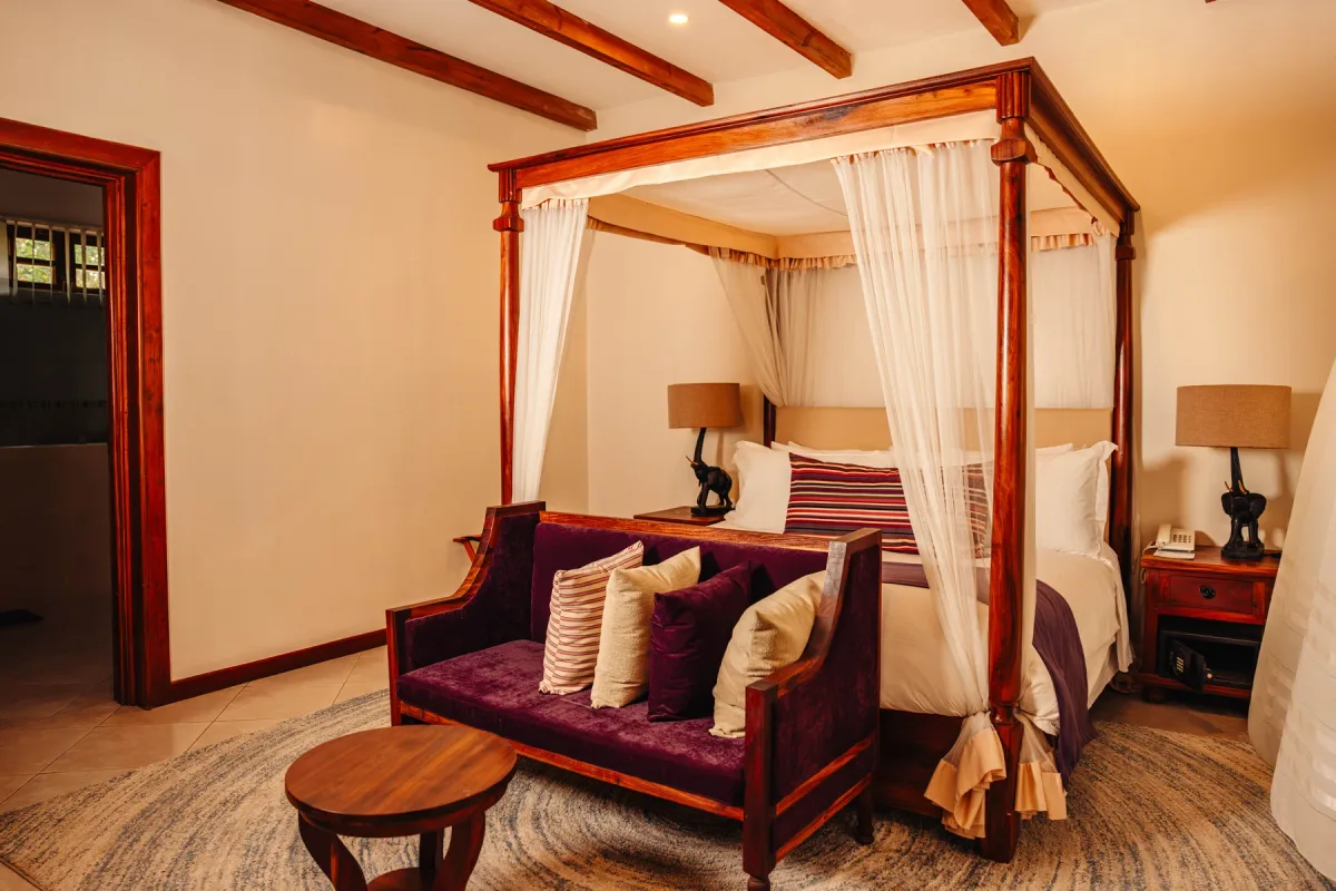 A four-poster bed with white drapes in a warmly lit lodge bedroom