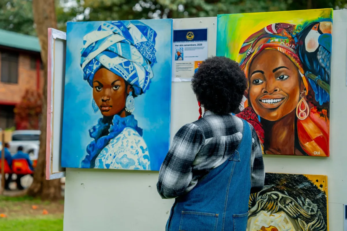 A visitor looking at colourful portrait paintings at The School of St Jude art exhibition