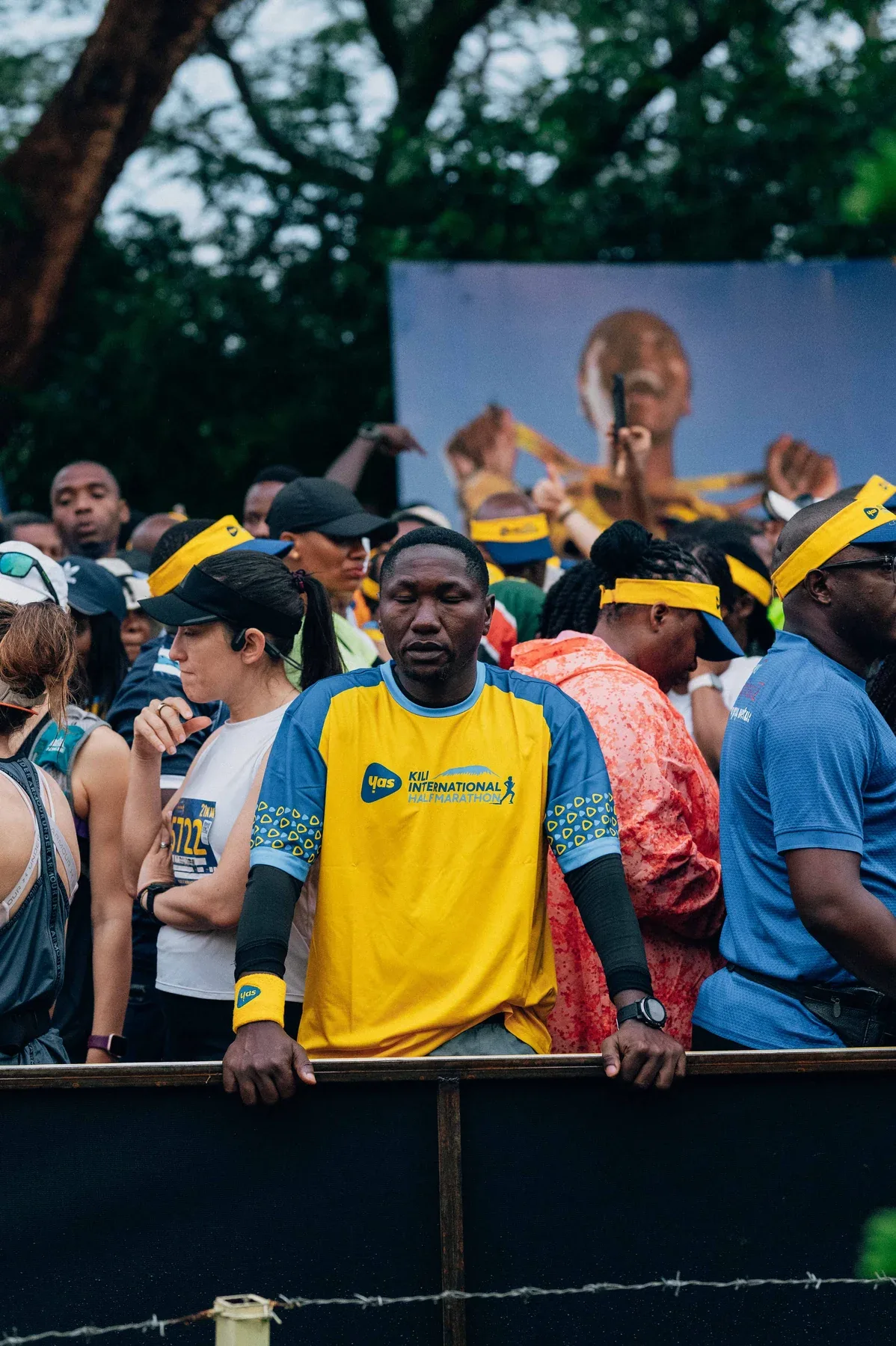 Runners in yellow event jerseys gathered near an outdoor stage